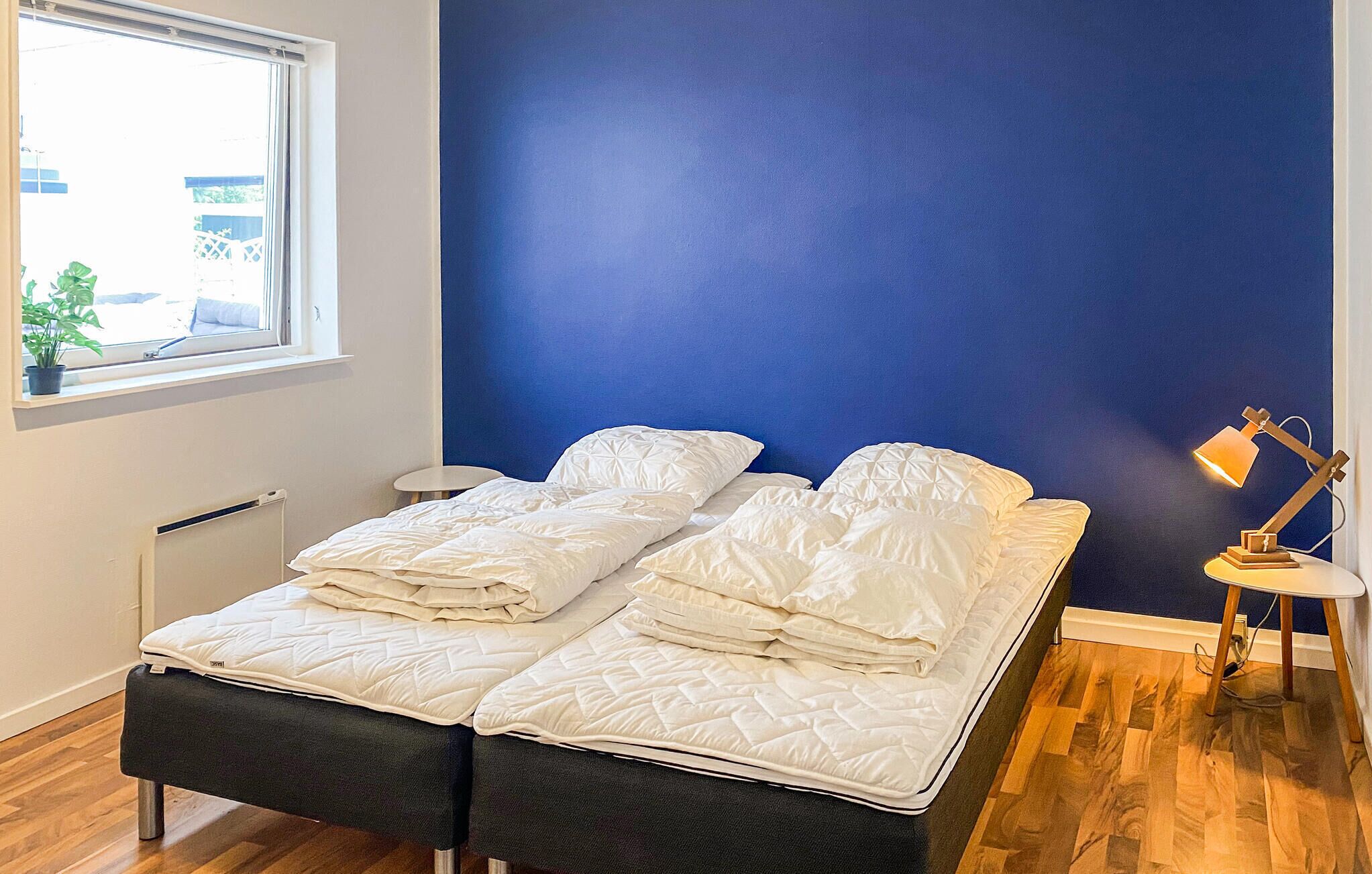 A room with a bed, a window, a small table, and a lamp.