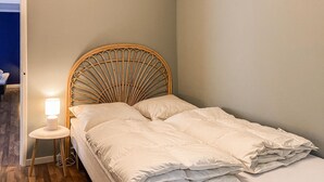 Un lit avec une tête de lit en osier, une lampe de chevet et une petite table.