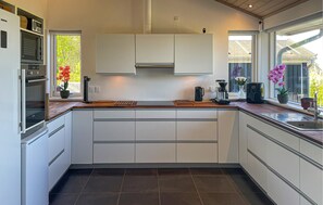 A modern kitchen with white cabinetry, a built-in oven, and a window with a view of greenery. - Beautiful home in Fårevejle with house sea view (Fårevejle)