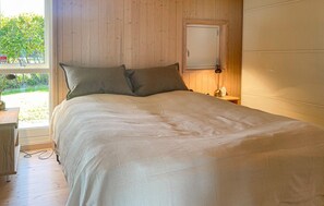 A bedroom with a bed, pillows, a nightstand, a lamp, and a window with a view of greenery. - Beautiful home in Fårevejle with house sea view (Fårevejle)