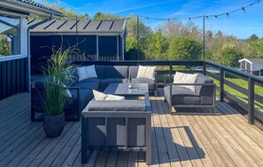 An outdoor deck with a sofa, chairs, and a table. - Beautiful home in Fårevejle with house sea view (Fårevejle)