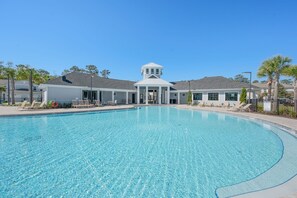 Una piscina con sillones de descanso, un pabellón techado y un cielo azul despejado.