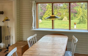 A wooden dining table with white chairs, a window with curtains, and a hanging lamp. - 3 bedroom cozy home in Kalundborg (Kalundborg)