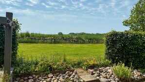 Ländliche Landschaft mit einer Steinmauer, einer Wiese und einer Hecke.