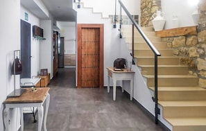 A hallway with a wooden door, a staircase with stone accents, and a small table with a lamp. - Beautiful home in Alcala la Real (Alcala la Real)
