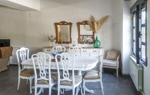 A dining area with a white table and chairs, two mirrors, a vase with dried plants, and a window with blinds. - Beautiful home in Alcala la Real (Alcala la Real)