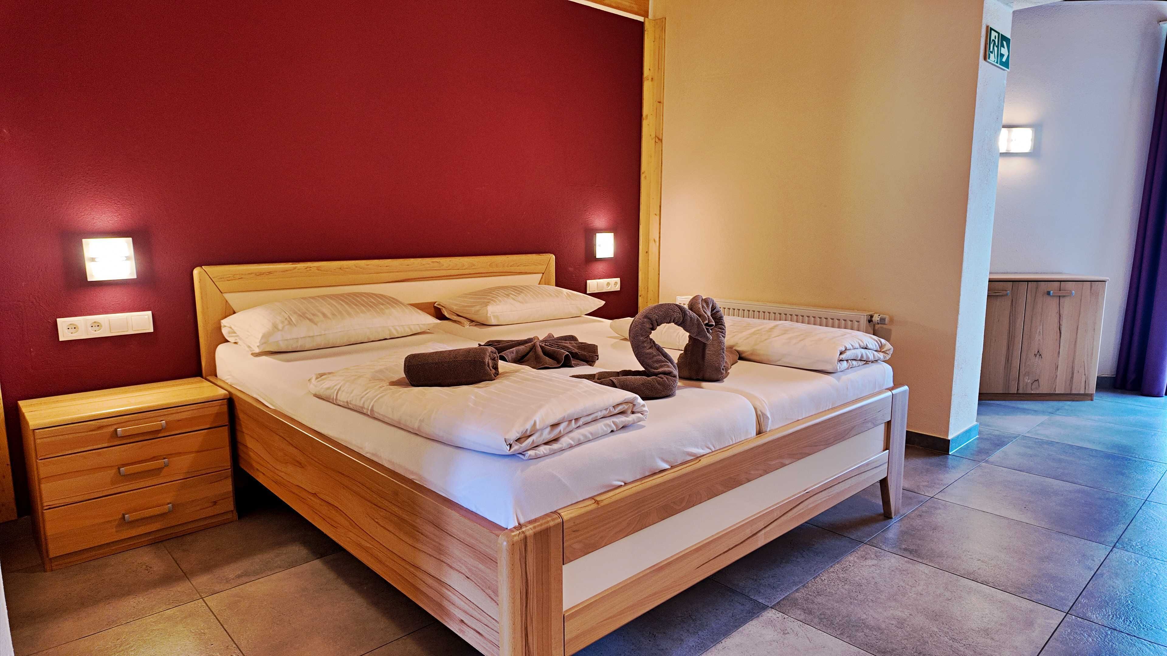 A neatly made bed with towels, a wooden headboard, and a nightstand with drawers.