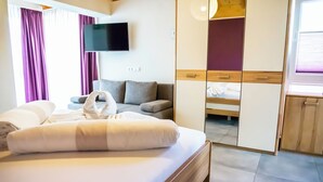 A hotel room with a bed, a sofa, a TV, and a wardrobe. - Butzkamm`s Ferien- & Studiohaus cultivated hospitality in the Sauerland (Wenden)