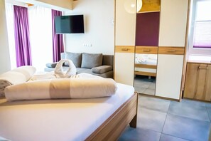 A hotel room with a bed, a sofa, a TV, and a wardrobe.