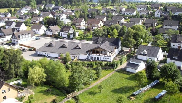 A residential area with houses, a large building with a sloped roof, and a pathway. - Butzkamm`s Ferien- & Studiohaus cultivated hospitality in the Sauerland (Wenden)