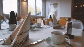 A dining table set with white napkins, a cup, a saucer, a knife, and a menu. - Butzkamm`s Ferien- & Studiohaus cultivated hospitality in the Sauerland (Wenden)
