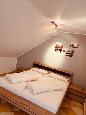 Ein Schlafzimmer mit einem hölzernen Bett, einem Nachttisch, einer Wandleuchte und drei gerahmten Bildern.