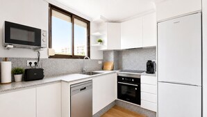 A modern kitchen with white cabinets, a built-in oven, a dishwasher, and a refrigerator. - 2 bedroom awesome apartment in Benicasim (Benicasim)