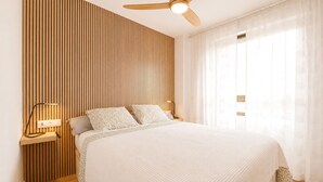 A bedroom with a bed, wooden panel wall, ceiling fan, bedside lamps, and sheer curtains. - 2 bedroom awesome apartment in Benicasim (Benicasim)