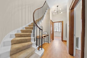 A staircase with carpeted steps, a wooden handrail, and a modern light fixture. - Castle Terrace: Stylish Victorian Townhouse in the Heart of Stirling (Stirling)