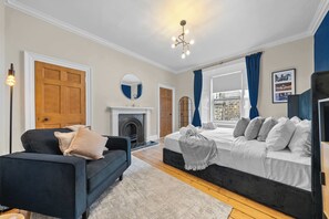 A bedroom with a bed, a sofa, a fireplace, and a view of the outside. - Castle Terrace: Stylish Victorian Townhouse in the Heart of Stirling (Stirling)