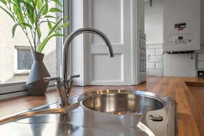 A kitchen with a stainless steel sink, a modern faucet, and a potted plant. - Castle Terrace: Stylish Victorian Townhouse in the Heart of Stirling (Stirling)