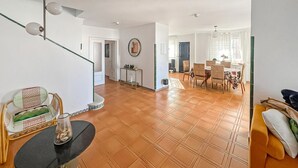 Amplia sala de estar con escalera, una mesa de comedor con sillas y un sofá.