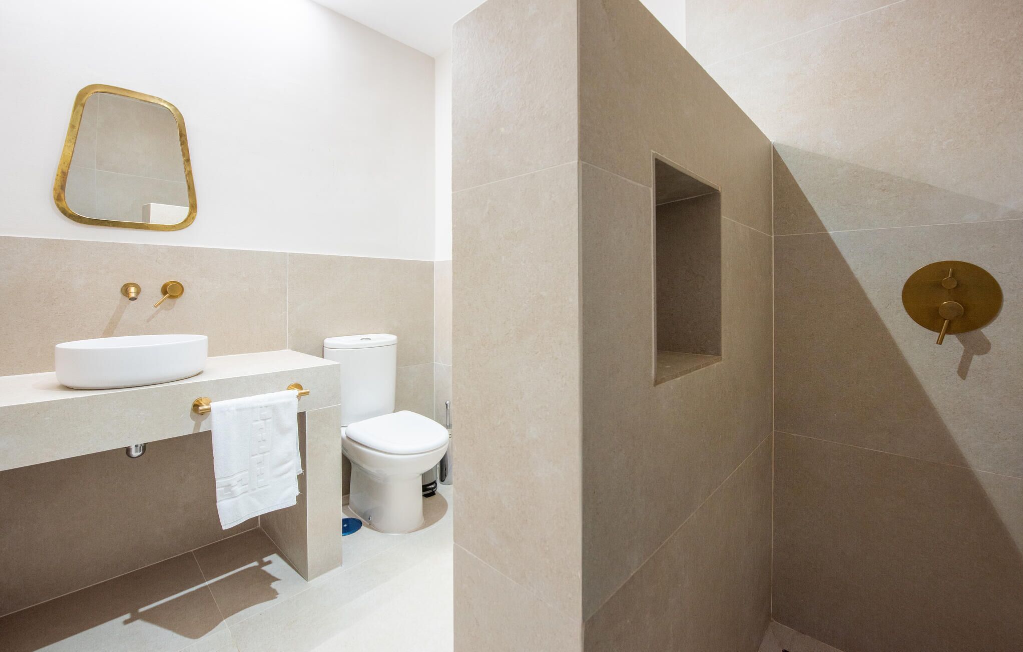 A modern bathroom with a white sink, toilet, and shower area.