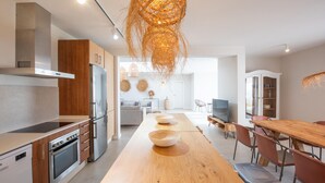 Eine moderne Küche mit einer langen Holzauskładung, Edelstahlgeräten und einer ungewöhnlichen Hängeleuchte.