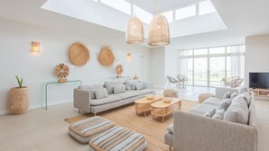 Ein modernes Wohnzimmer mit einer Couch, Poufs und einem Fernseher.