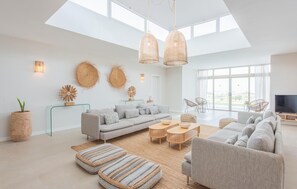 Ein modernes Wohnzimmer mit einer Couch, Poufs und einem Fernseher.