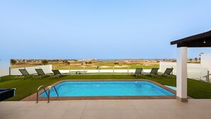 Ein Swimmingpool mit Blick auf einen Golfplatz.