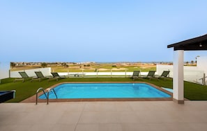 Ein Swimmingpool mit Blick auf einen Golfplatz.
