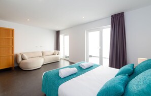 Ein modernes Hotelzimmer mit Bett, einer Sitzecke, einem Holzschrank und einem großen Fenster.