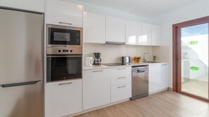 Eine moderne Küche mit weißen Schränken, einem Backofen, einer Mikrowelle, einer Kaffeemaschine und einem Geschirrspüler.