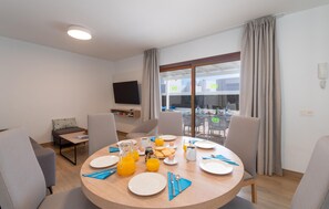 A dining area with a round table set for breakfast, a TV on the wall, and a view of the outdoor patio. - Nice home in Lanzarote with private swimming pool, can be inside or outside (Lanzarote)