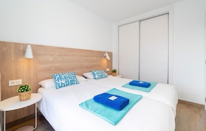A hotel room with two beds, a wooden headboard, bedside lamps, a small table with a plant, and a large window. - Nice home in Lanzarote with private swimming pool, can be inside or outside (Lanzarote)