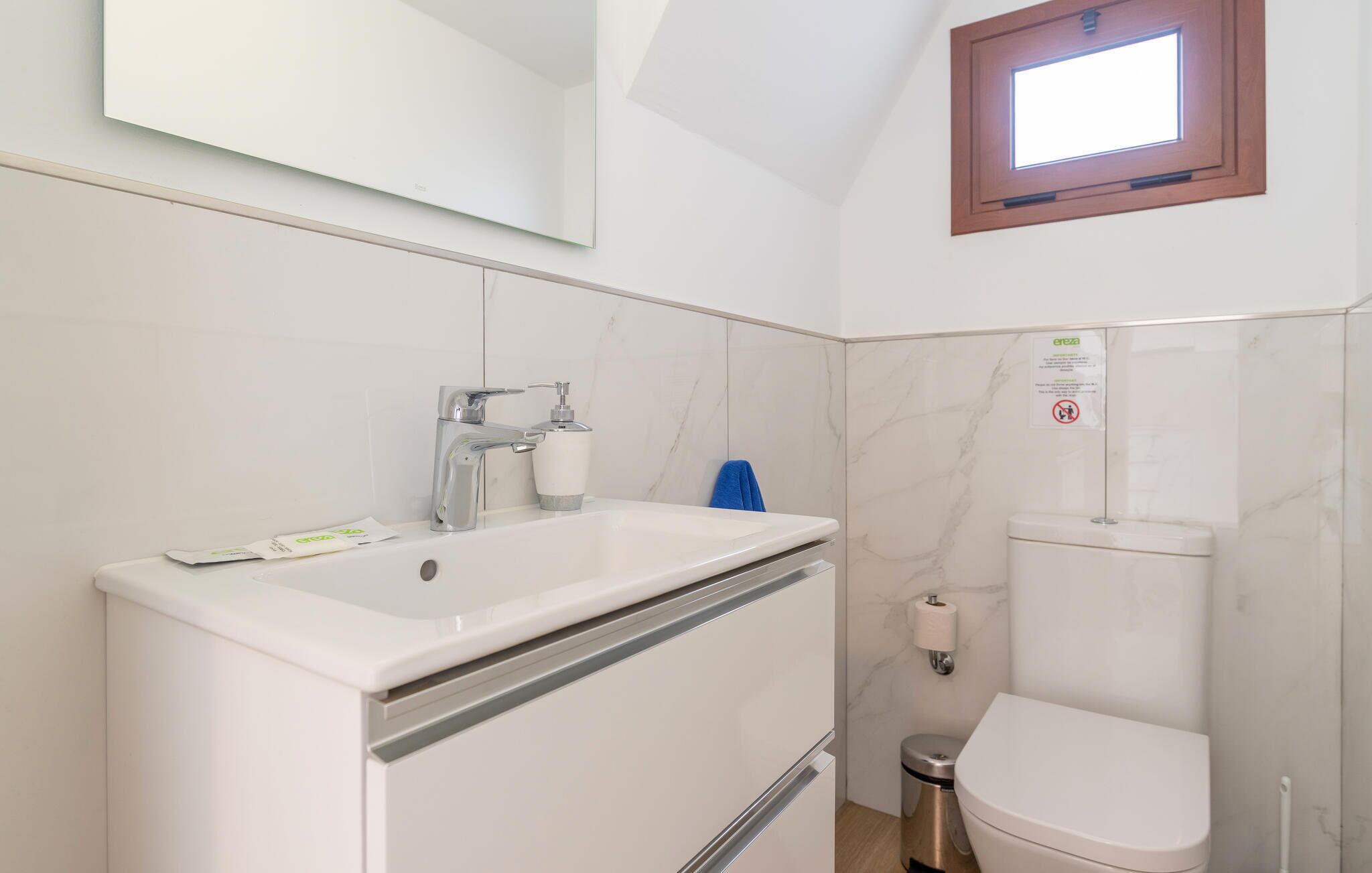 A modern bathroom with a white sink, chrome faucet, and a toilet.