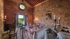 A rustic interior with stone walls, wooden chairs, a table with a white cloth, and candles. - Casale di Valle - Historic House in the Heart of Chianti (Toscana)