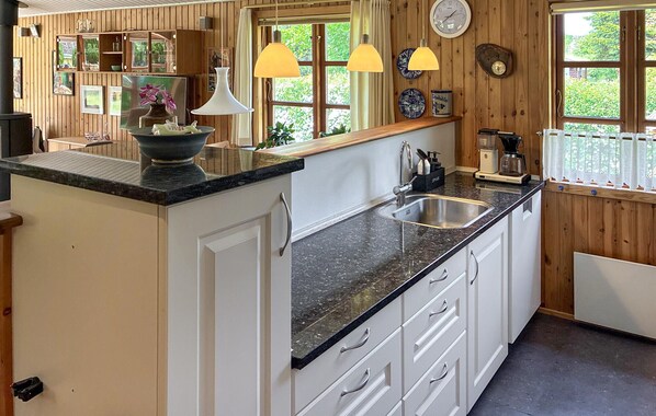 A kitchen with a central island, a sink, and wooden walls. - 3 bedroom beautiful home in Eskebjerg (Eskebjerg)