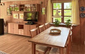 A wooden-paneled room with a television, wooden cabinet, dining table, chairs, and a window with curtains. - 3 bedroom beautiful home in Eskebjerg (Eskebjerg)