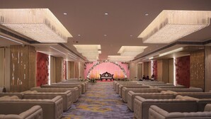 A hotel interior with rows of seating, a stage with floral decorations, and chandeliers. - Hotel Raaj Palace (Agra)