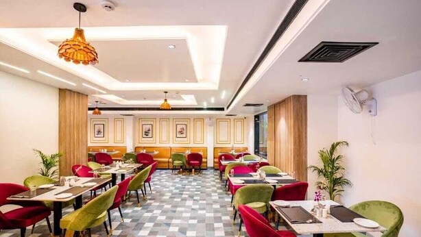 A hotel dining area with checkered flooring, multiple tables, and chairs. - Hotel Raaj Palace (Agra)