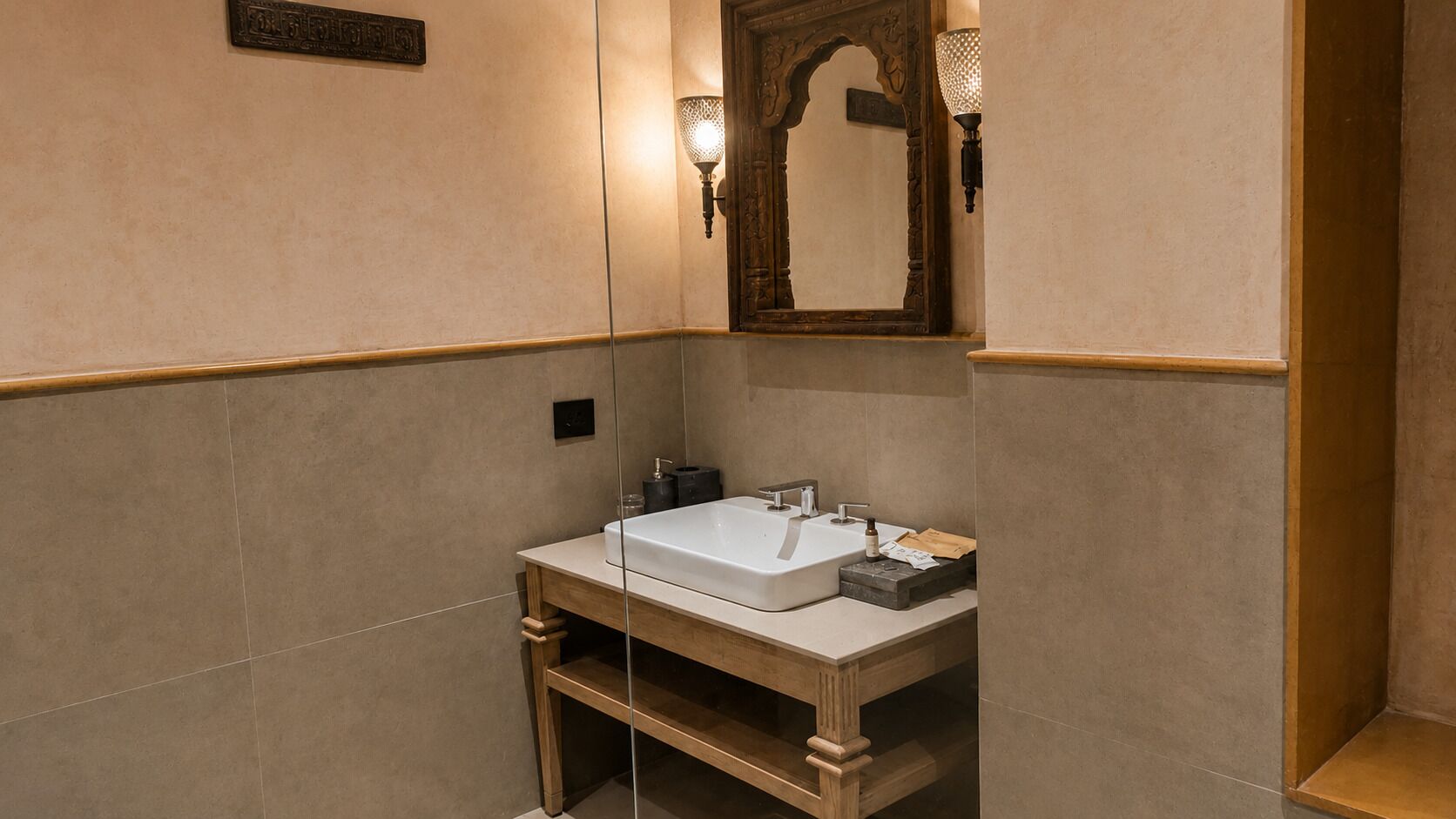 Un bagno con un lavandino bianco, una cassettiera in legno e uno specchio con cornice decorata.