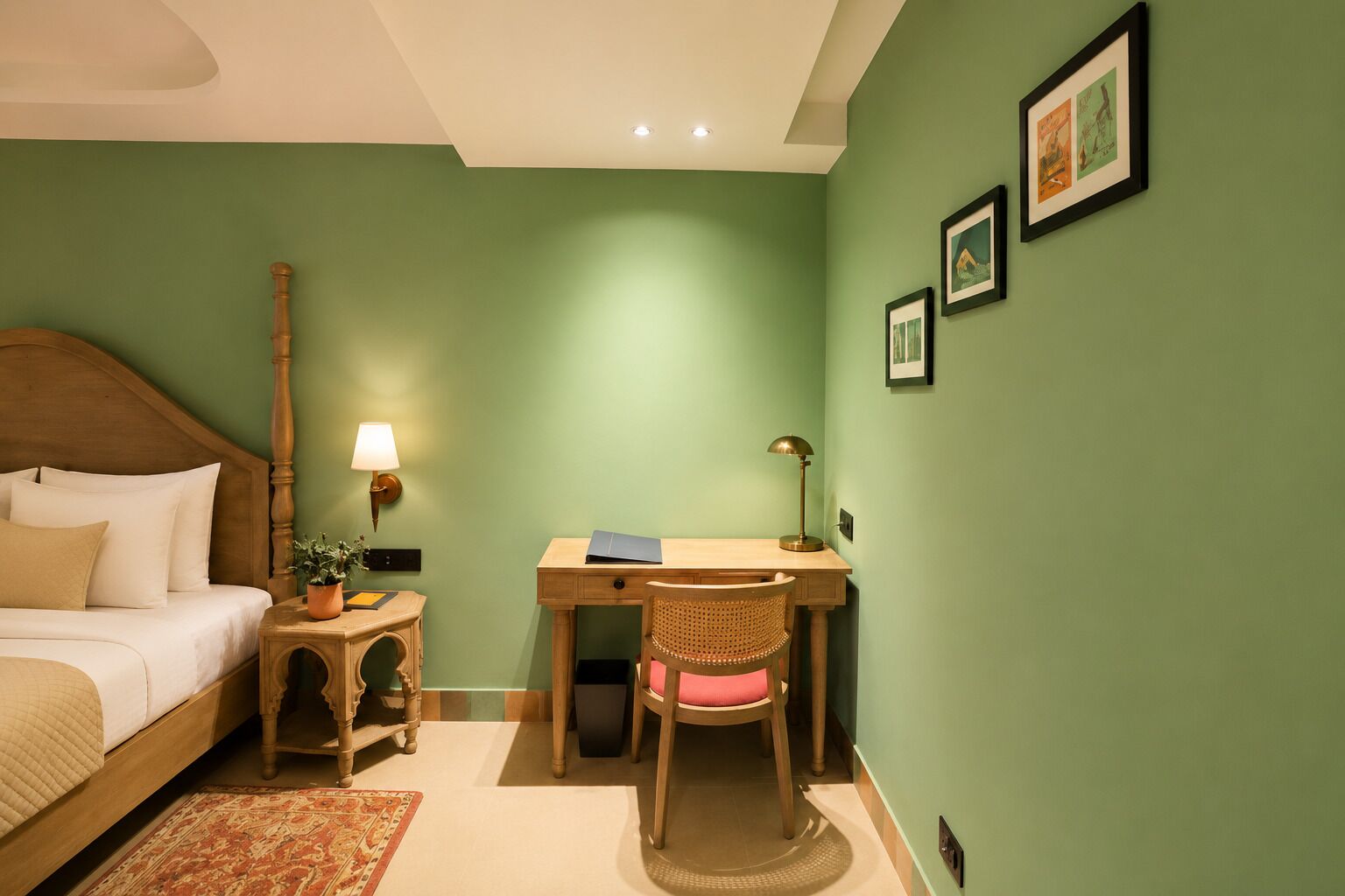 A room with a bed, desk, chair, lamp, and wall art.
