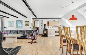 A modern loft with exposed beams, a central fireplace, a dining area, and a kitchen with wooden cabinets. - 5 bedroom lovely home in Sydals (Sydals)