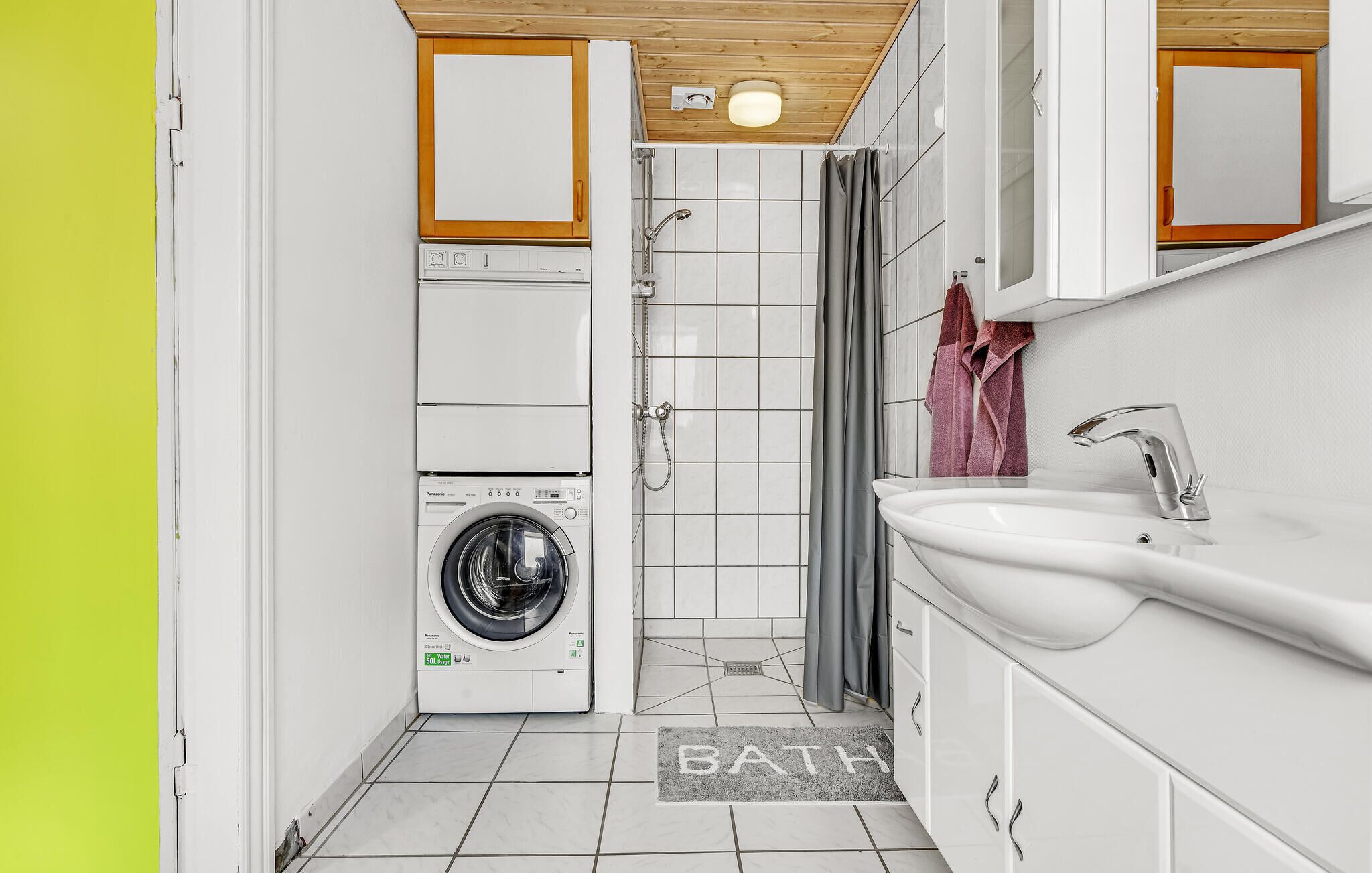 Een kleine badkamer met een wasmachine, een douche en een wastafel.