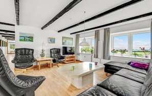 A modern living room with a sofa, chairs, a coffee table, a TV, and artwork on the walls. - 5 bedroom lovely home in Sydals (Sydals)