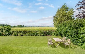 A grassy outdoor area with a table and chairs, surrounded by hedges and trees. - 5 bedroom lovely home in Sydals (Sydals)