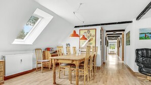 A dining area with a wooden table and chairs, a radiator, and a skylight.