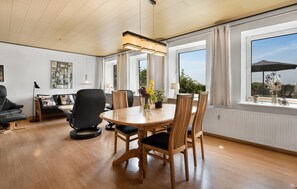 A spacious room with a wooden dining table, chairs, a sofa, and a large window with curtains. - Lovely home in Sydals with WiFi (Sydals)