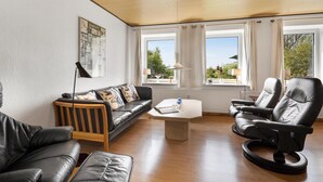 A living room with a sofa, two chairs, a coffee table, and a window with curtains. - Lovely home in Sydals with WiFi (Sydals)