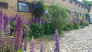 A cobblestone street with purple flowers and a brick building with a window and a door. - Lovely home in Sydals with WiFi (Sydals)