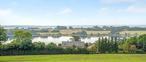 Un paysage rural avec un lac, des champs et une maison.
