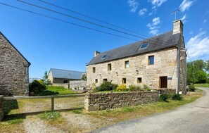 A stone building with a sloped roof, multiple windows, and a visible chimney. - Stunning home in Ploumillau with WiFi (Ploumillau)